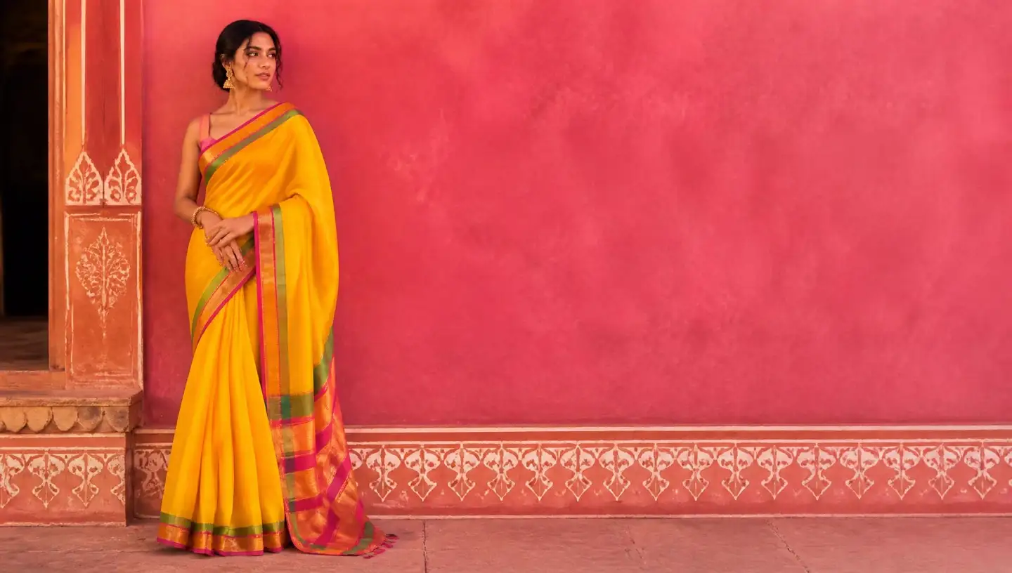 Model in a marigold handloom cotton saree against a bright pink Rajasthani wall